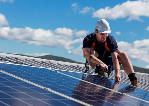 Ein Mann montiert Solarplatten auf einem Dach